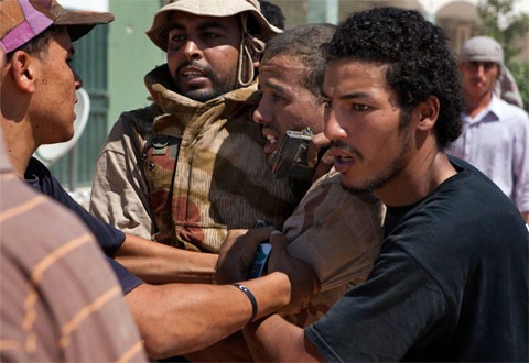 Binh sĩ phe đối lập ở Libya áp giải một lính bắn tỉa thuộc lực lượng trung thành với Gadhafi mà họ bắt được tại Zawiya ở phía tây Libya hôm 13/8. Sau khi liên tục bị dọa nạt, người bị bắt, hiện vẫn chưa rõ tên tuổi, được đưa lên một chiếc xe để tới thành phố Zintan ở phía bắc. Ảnh: AP